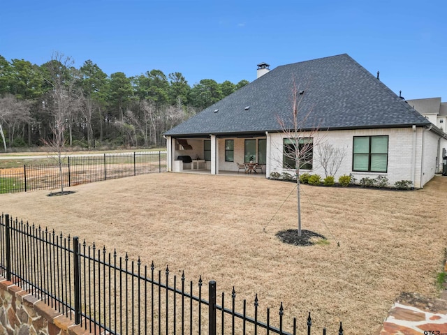 back of house featuring a patio, a yard, fence, and brick siding