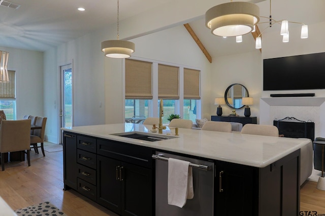 kitchen featuring dark cabinets, pendant lighting, a kitchen island with sink, and stainless steel dishwasher