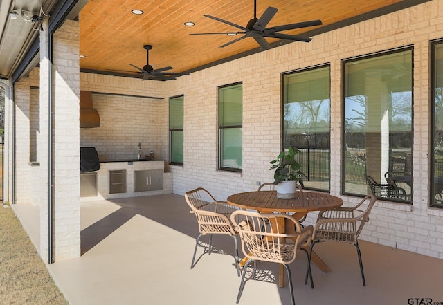 view of patio featuring outdoor dining area, a grill, an outdoor kitchen, and a ceiling fan