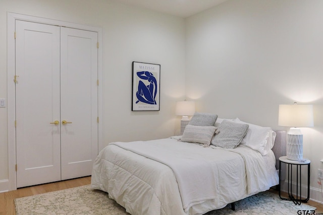 bedroom featuring light wood finished floors, baseboards, and a closet