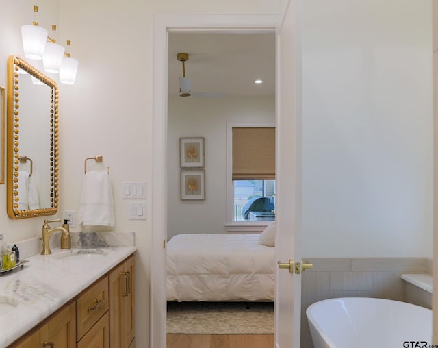 ensuite bathroom featuring a freestanding bath, vanity, ensuite bath, and wood finished floors