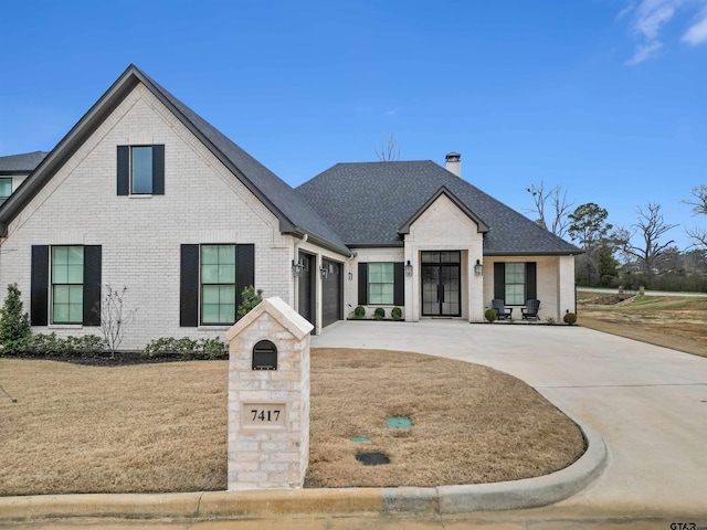 view of front of property with driveway, a garage, a shingled roof, brick siding, and a front yard