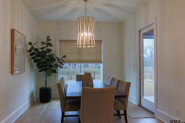 dining space featuring baseboards, light wood finished floors, and an inviting chandelier