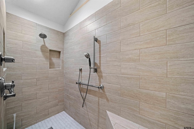 full bath featuring lofted ceiling and a tile shower