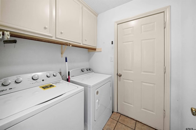 laundry area with cabinet space, independent washer and dryer, a textured ceiling, and light tile patterned flooring