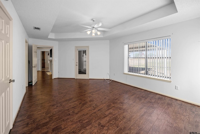 spare room featuring a tray ceiling, a textured ceiling, baseboards, and wood finished floors