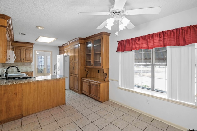 kitchen with light tile patterned floors, white appliances, a sink, visible vents, and brown cabinets