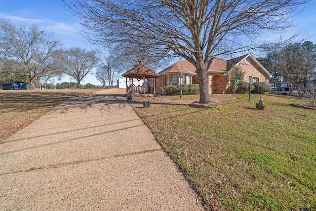 view of front of property featuring brick siding, a front lawn, and a gazebo