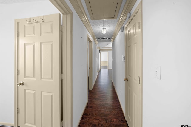 hallway with dark wood-style flooring, visible vents, attic access, a textured ceiling, and baseboards