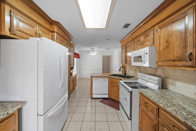 kitchen with visible vents, brown cabinetry, light tile patterned flooring, a sink, and white appliances