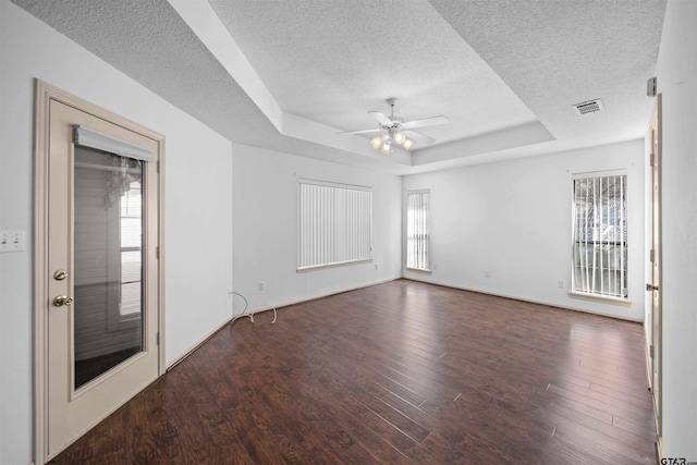 unfurnished room featuring plenty of natural light, a tray ceiling, ceiling fan, and wood finished floors