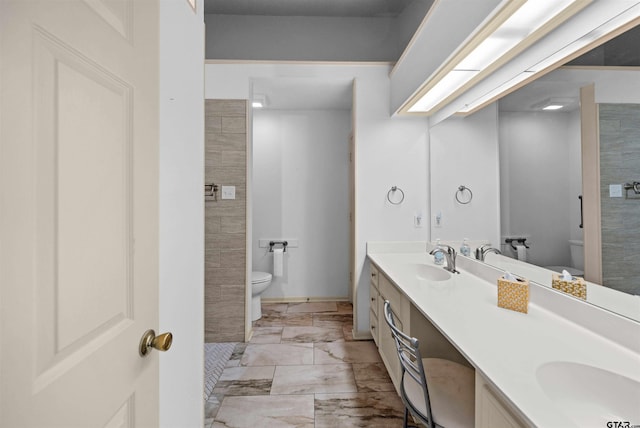 bathroom with a sink, toilet, and double vanity