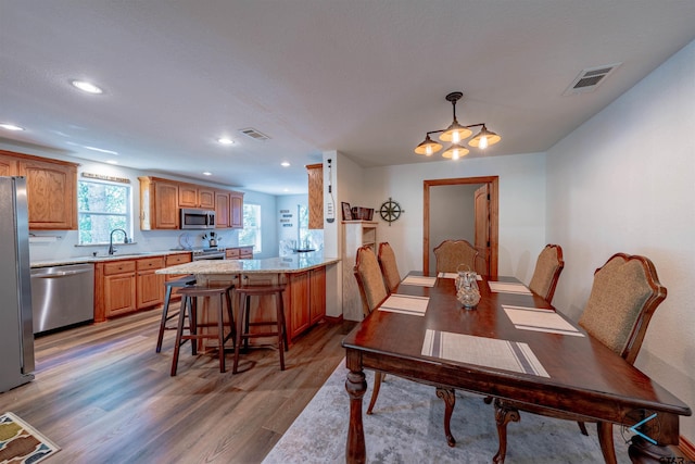 dining space with sink, an inviting chandelier, and hardwood / wood-style floors