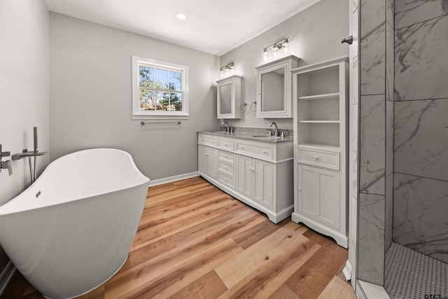 full bathroom featuring double vanity, a sink, a soaking tub, and wood finished floors
