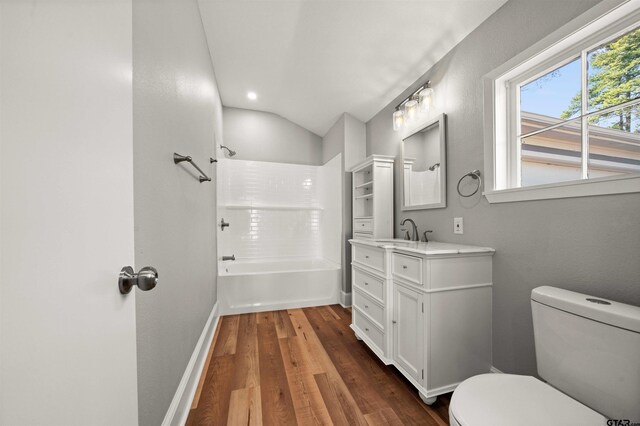 bathroom featuring vanity, wood finished floors, toilet, lofted ceiling, and  shower combination