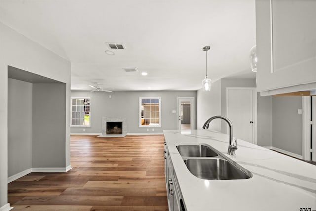 kitchen with a fireplace, a sink, wood finished floors, and visible vents