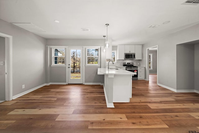 kitchen with visible vents, stainless steel appliances, a peninsula, and a sink