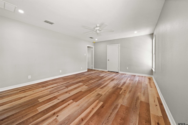 empty room featuring a ceiling fan, visible vents, baseboards, and light wood-style floors