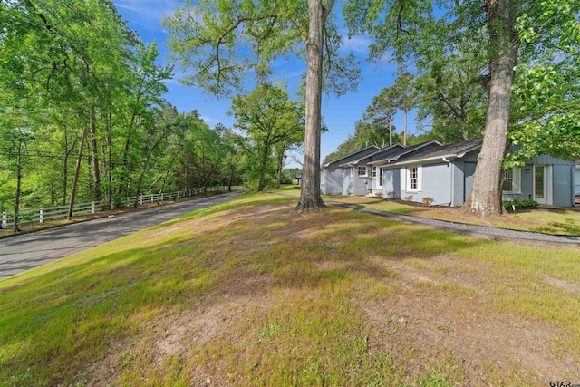 view of yard featuring driveway and fence
