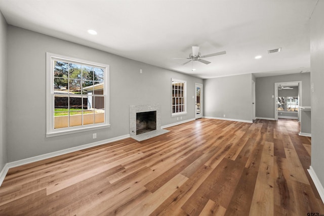 unfurnished living room featuring baseboards, ceiling fan, and a fireplace with flush hearth