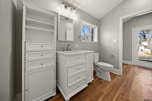 bathroom featuring toilet, vanity, wood finished floors, and baseboards