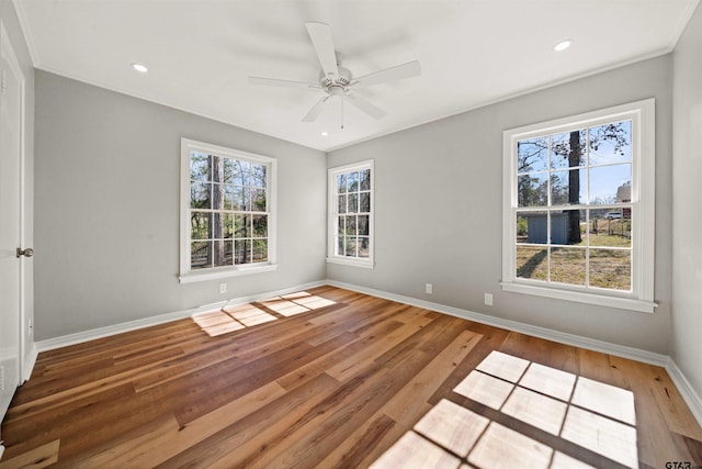 spare room featuring baseboards, wood finished floors, a healthy amount of sunlight, and ceiling fan