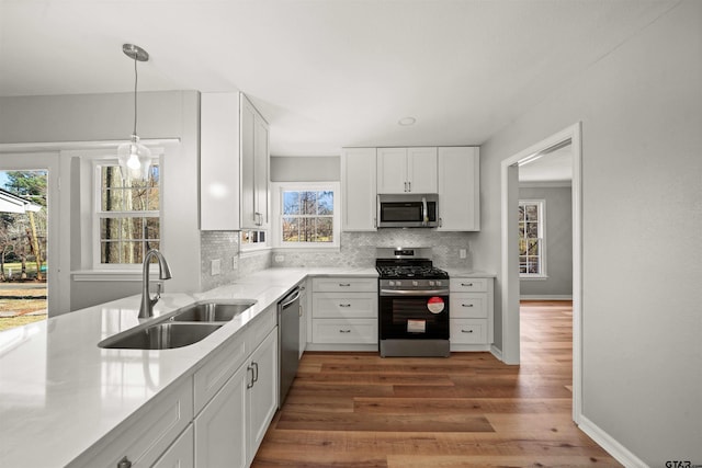 kitchen with white cabinets, appliances with stainless steel finishes, decorative backsplash, and a sink