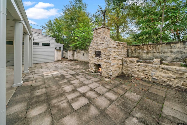 view of patio / terrace with fence and an outdoor stone fireplace