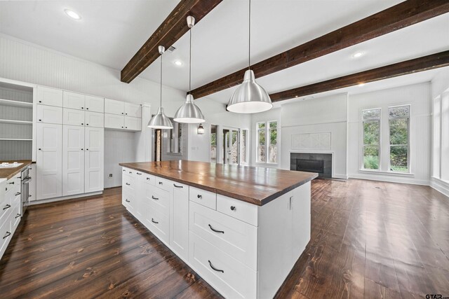 kitchen with dark wood finished floors, pendant lighting, a fireplace, and butcher block countertops