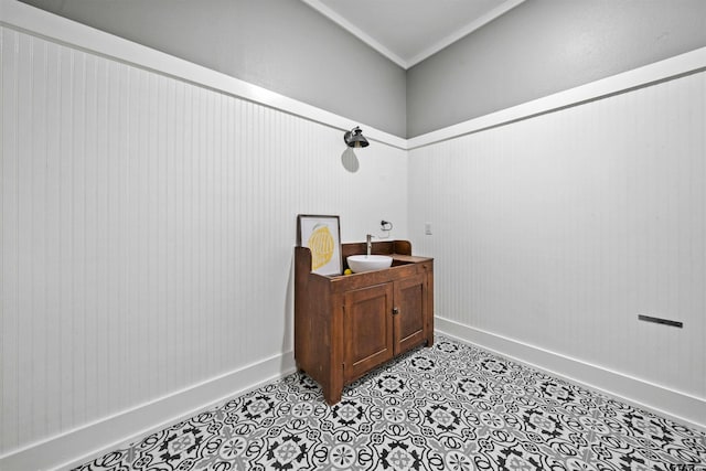 interior space featuring crown molding, baseboards, and a sink