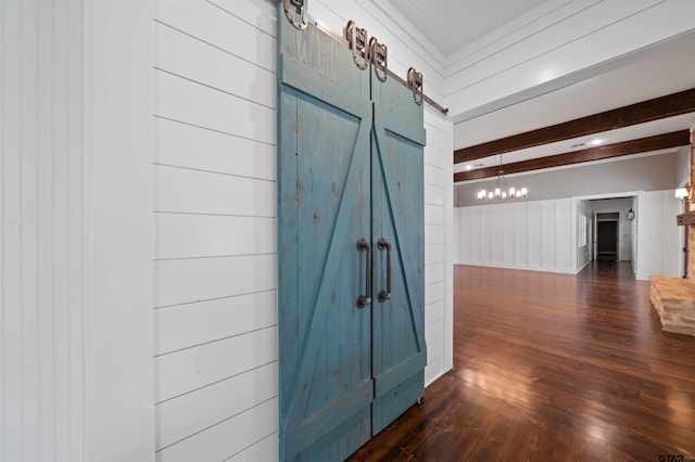 interior space with a barn door, beamed ceiling, dark wood finished floors, and an inviting chandelier