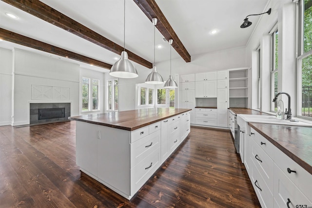 kitchen featuring a glass covered fireplace, open shelves, dark wood-style flooring, and wood counters