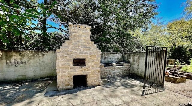 view of patio / terrace featuring an outdoor stone fireplace and fence