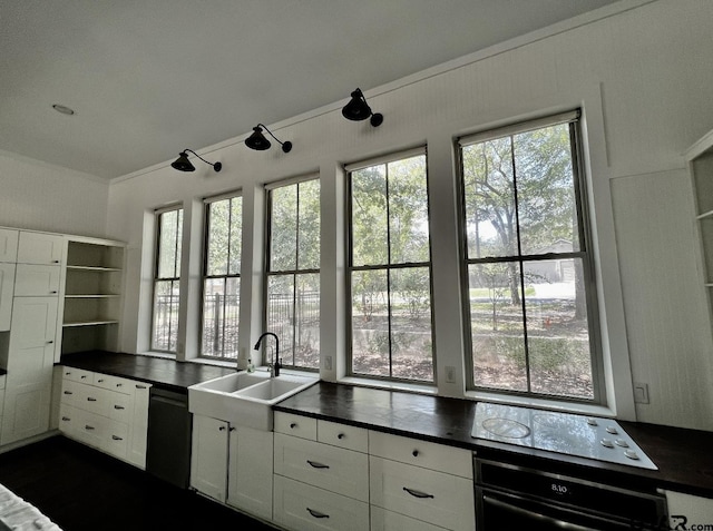 kitchen with wall oven, dark countertops, dishwasher, and a sink