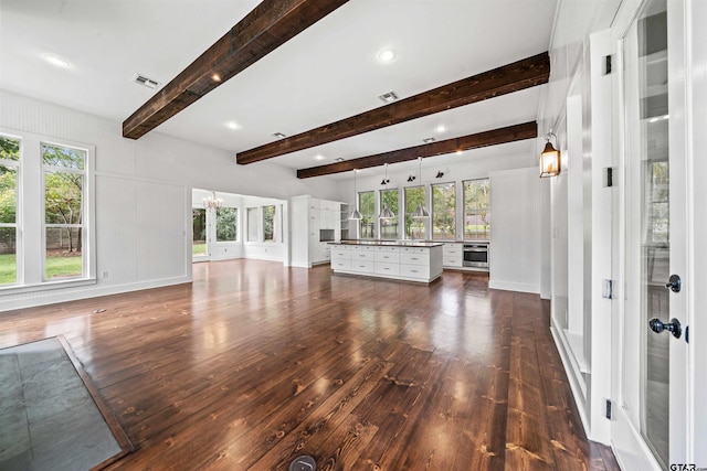 unfurnished living room featuring dark wood finished floors, visible vents, and a healthy amount of sunlight