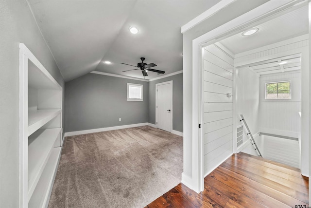 additional living space featuring a ceiling fan, baseboards, dark wood finished floors, lofted ceiling, and dark colored carpet