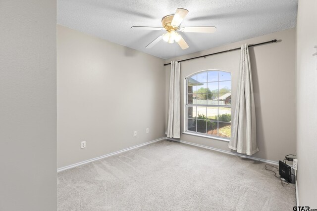 spare room with a textured ceiling, ceiling fan, baseboards, and carpet