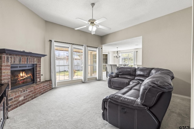 carpeted living room with ceiling fan with notable chandelier, a fireplace, and a textured ceiling
