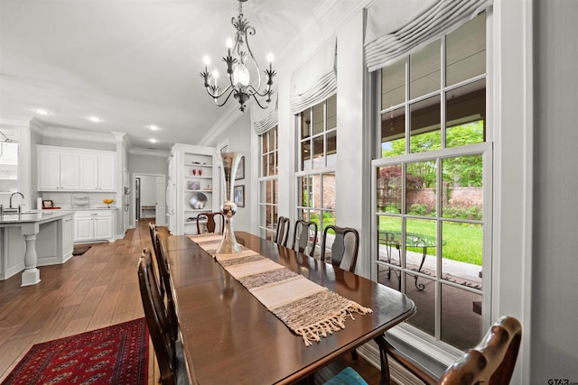 dining area featuring ornamental molding, sink, wood-type flooring, and an inviting chandelier