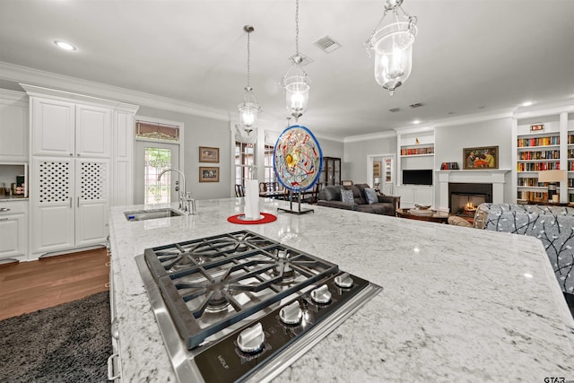 kitchen with light stone countertops, stainless steel gas cooktop, sink, built in features, and white cabinets