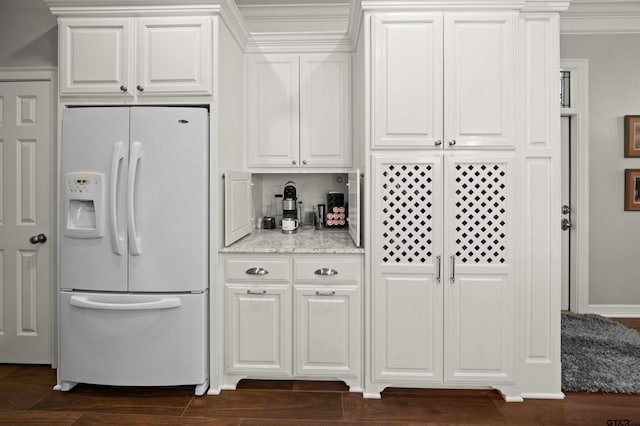 kitchen featuring white cabinets, ornamental molding, white fridge with ice dispenser, and dark wood-type flooring