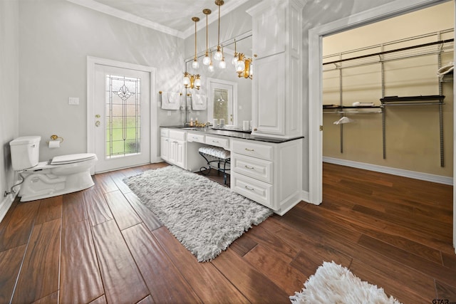 bathroom featuring toilet, vanity, wood-type flooring, and ornamental molding