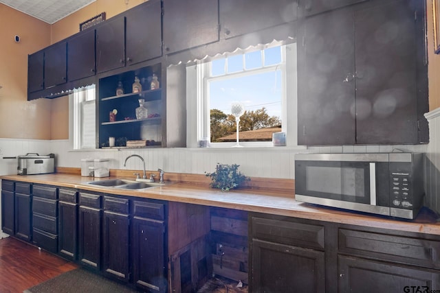 kitchen featuring blue cabinetry, dark hardwood / wood-style flooring, sink, and wooden counters