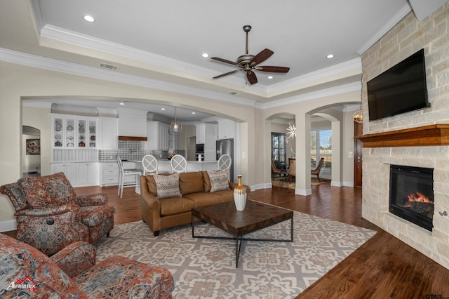 living room featuring a fireplace, ornamental molding, a tray ceiling, and hardwood / wood-style floors