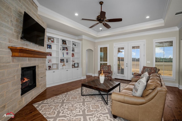 living room with ornamental molding, a fireplace, hardwood / wood-style floors, and a tray ceiling