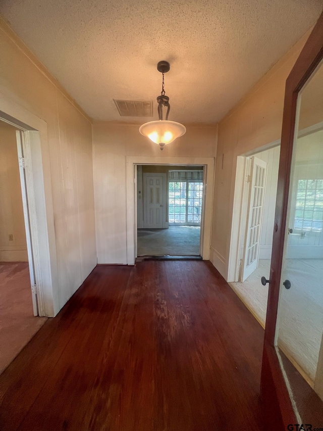 unfurnished dining area with a textured ceiling and dark hardwood / wood-style floors