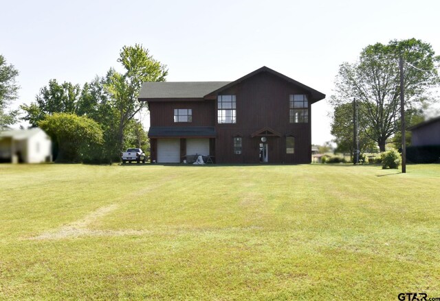 rear view of house with a garage and a yard