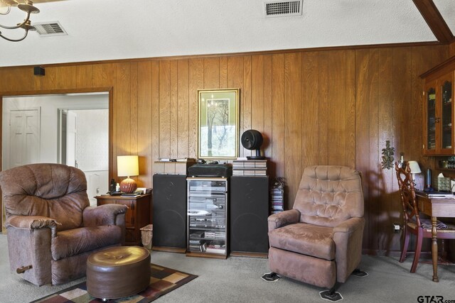 carpeted living room with wood walls and a textured ceiling