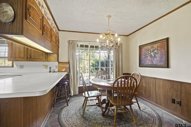 tiled dining space featuring a textured ceiling, wooden walls, an inviting chandelier, and crown molding