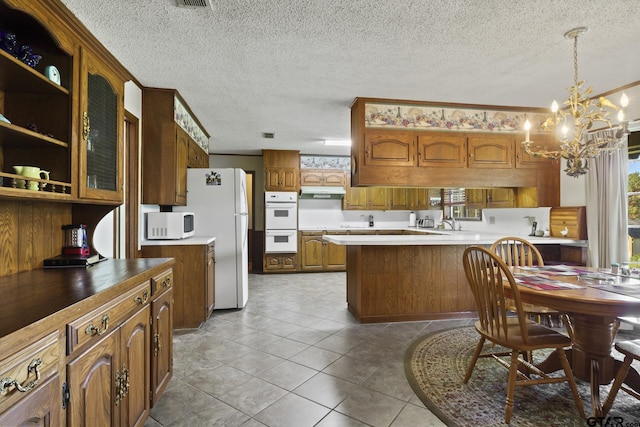 kitchen with a textured ceiling, white appliances, decorative light fixtures, and a notable chandelier